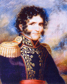 Head and shoulders of curly haired young man with bushy sideburns and moustache, dressed in 19th century clothes.