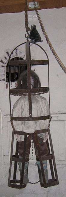photo of a cage with a human-sized dummy held tightly within