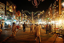 picture taken in evening, having a bazaar with people walking around, and food shops.
