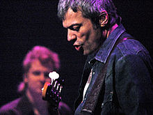 A man on stage sings and plays the guitar