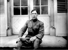 A man in a military uniform, sitting on a bench
