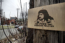 A sign nailed to a tree shows the image of a man and reads "Free Leonard Peltier.