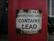 a closeup of a red gas pump with a warning label that reads, "for use as a motor fuel only" (in larger writing) "contains lead" (in smaller writing) "(tetraethyl)"
