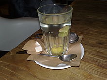 A glass with a spoon and cubed sugar on a wooden table