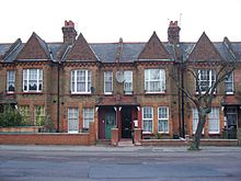 A row of two-storey red brick houses with sharply angled roofs and large windows