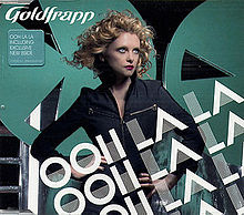 CD cover with a blond-haired woman at the centre standing with her hands on her hips and looking off to the right of the image. Text overlays the woman and the bottom right of the image saying "Ooh La La" three times. Text in the upper left corner says "Goldfrapp" along with a small text box stating "Ooh La La Including Exclusive New BSide". In the background is a black wall along with two teal-colored circles with triangle-shaped holes cut out of them.