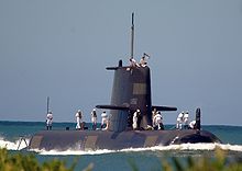A submarine with people wearing white uniforms standing on the outer hull