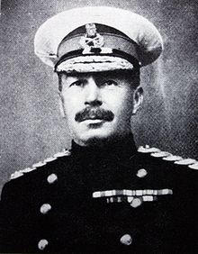 Monochrome portrait of officer in cap and uniform. Cap has white cover. Medal ribbons and shoulder braid of Flag Officer visible.