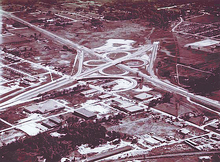 A four-leaf clover shaped highway junction, located in the midst of developing suburbs.