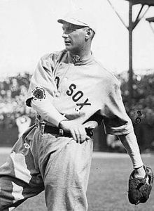 A man wearing a baseball uniform with "Red Sox" displayed on the chest caught in the midst of throwing a baseball.