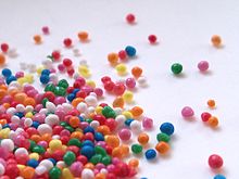 Very small, brightly coloured round sugar decorations scattered across a surface.