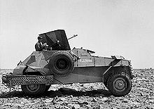 A four-wheeled armoured car, faces to the right, on a stony-desert backdrop.