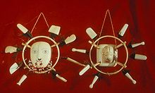 Photo of 2 masks. In the center is the image of a face, surrounded by a ring, in turn surrounded by 8 white rectangular pieces