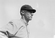 A man wearing a baseball cap and jersey devoid of any markings looks to the right.