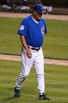 Man wearing a blue baseball uniform walking on a baseball infield