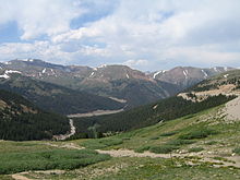 Several mountains with scars from roads visible at the base and up the sides