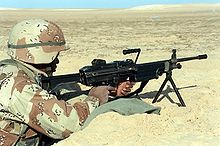 A U.S. Marine with an M249 SAW on its bipod manning a foxhole during the 1991 Gulf War