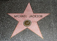 A pink star with a gold colored rim and the writing "Michael Jackson" in its center. The star is indented into the ground and is surrounded by a marble colored floor.