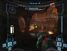 View of volcanic caverns; an enemy with a jetpack shoots a green ray at the player, whose weapon (a large cannon) is visible in the corner of the screen. The image is a simulation of the heads-up display of a combat suit's helmet, with a crosshair surrounding the enemy and two-dimensional icons relaying game information around the edge of the frame.