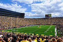 Crowded stadium with yellow-colored "Michigan" written on a green field