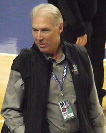 A man in his sixties wearing a press credential around his neck