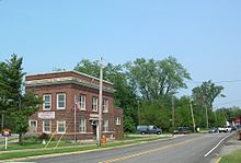 A large square red brick building on a triangular lot.