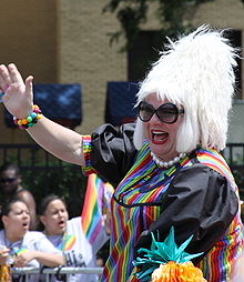 Miss Foozie waves during a pride parade.