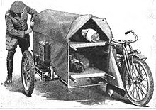 A man securing the canvas cover on a motorcycle sidecar containing two patients