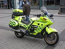 Yellow motorcycle with green battenberg livery parked without rider on a pavement