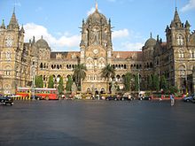 A brown building with clock towers, domes and pyramidal tops. Also a busiest railway station in India.[203] A wide street in front of it