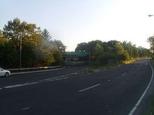 A four-lane road at dusk approaching a large split