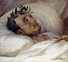 Gold-framed portrait painting of a gaunt middle-aged man with receding hair and laurel wreath, lying eyes-closed on white pillow with a white blanket covering to his neck and a gold Jesus cross resting on his chest