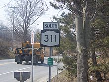 A sign depicting the 311 designation. The road itself is visible in the background.