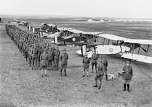 Men standing in files behind biplanes. They are wearing slouch hates, service jackets and breeches