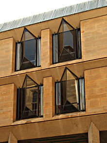 Four windows from a two-storey stone building projecting in a V-shape