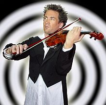 Man dressed in a tailcoat and open-necked white shirt, playing a violin