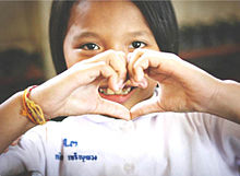 Thai student at Tesaban 3 School making a heart with her hands.