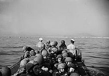 Men in crowded boat approaching a distant shore