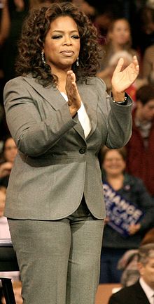 Picture of a woman in a suit clapping.