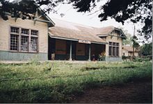 A low building with large windows sits behind uncut grass