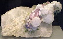 A white mineral, from which white and pale pink crystals protrude