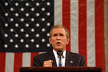 President Bush delivering a speech in front of the American flag