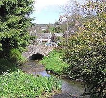 Stone bridge over water, surrounded by vegetation.
