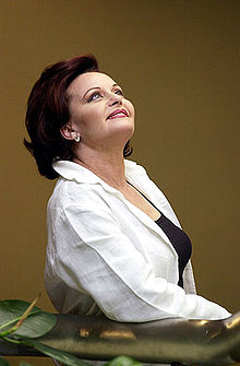 A woman with a white blouse with her head up, looking to the ceiling.