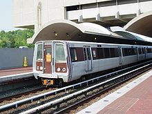 An exterior perspective view of a train, with its distinct brown and metallic design, at a station platform.