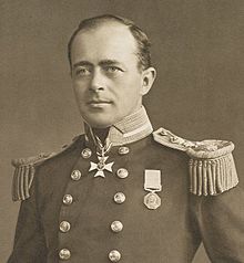  Man with receding hairline, looking left, wearing naval uniform with medals, polished buttons and heavy shoulder decorations