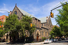 A view from across the street of St. Paul's Church in Carroll Gardens, Brooklyn—a brick building with a small stained glass windows and a grey roof