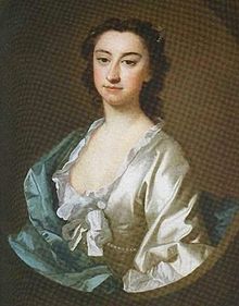 Dark-haired, dark-eyed woman with a large nose, wearing a low-cut white blouse