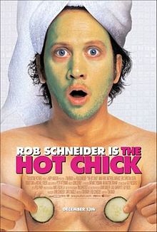 Rob Schneider with a towel covering his hair, and green facial cream covering his face, and holding two cucumber slices in his hands.