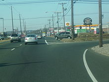 a one-way two lane road lined with businesses and power lines